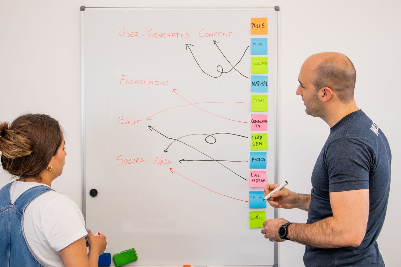gallery-03 Two colleagues brainstorm ideas on a whiteboard during a creative strategy session.